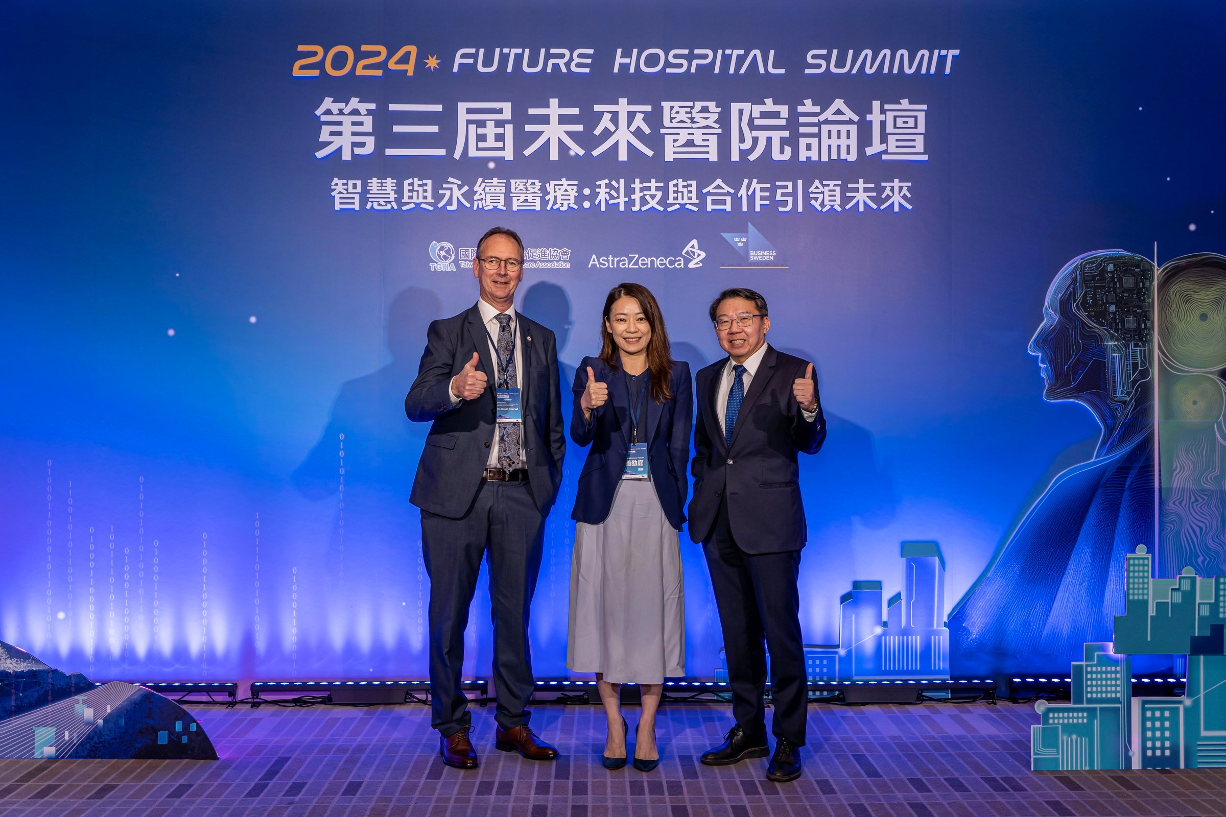 David Konrad and two other people giving thumbs up on stage of the Future Hospital Summit 2024