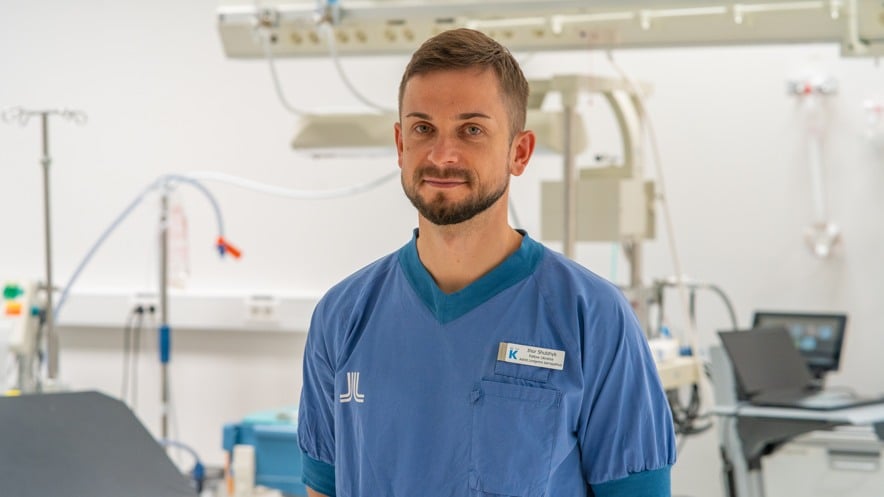 A man in scrubs standing in a hospital room